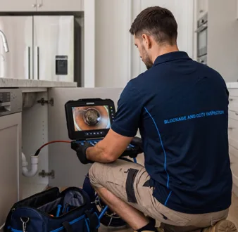 Plumber clearing a blocked toilet in a Carlingford bathroom